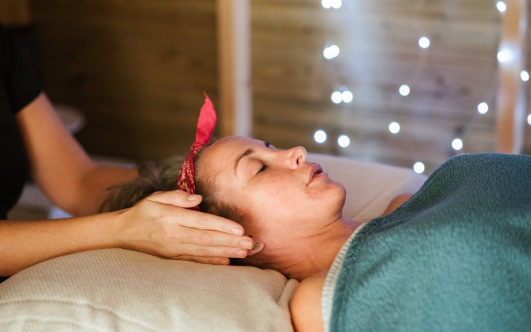 close up of masseuse with hands near ears of woman