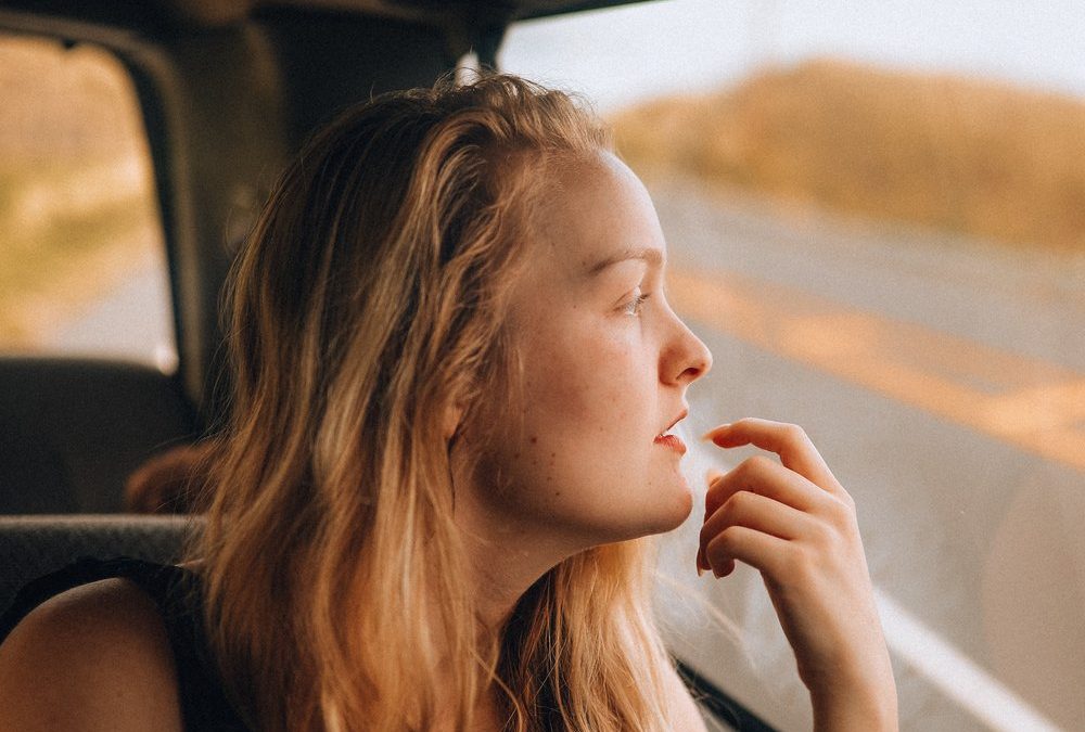 woman looking through car window with a thoughtful look