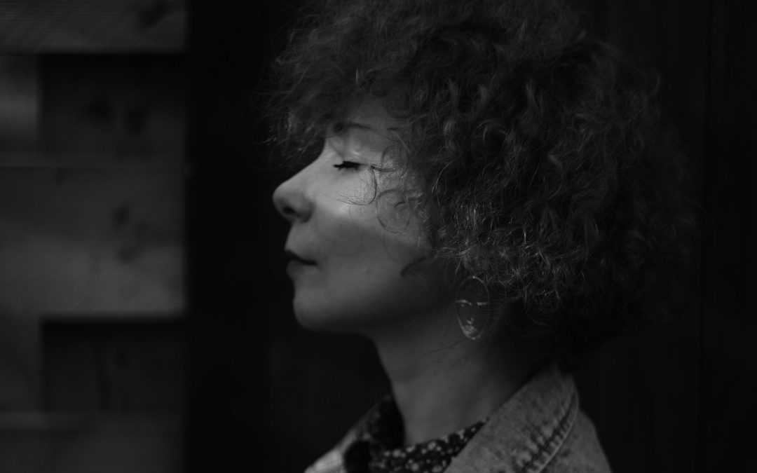 black and white portrait of curly hair woman with eyes closed